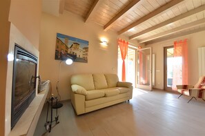 Ein Wohnzimmer mit beiger Couch, einem Stadtgemälde, einem Kamin und Holzboden.