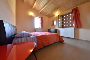 A bedroom with a bed, a desk, a window with curtains, a radiator, and a mirror. - Villa 'In Collina Con Piscina' with private pool, private garden and Wi-Fi (Lucca)