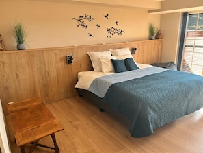 A bedroom with a bed, bedside tables, a wooden headboard, a wall decoration of birds, and a window. - Cozy Chalet near Durbuy (Somme-Leuze)