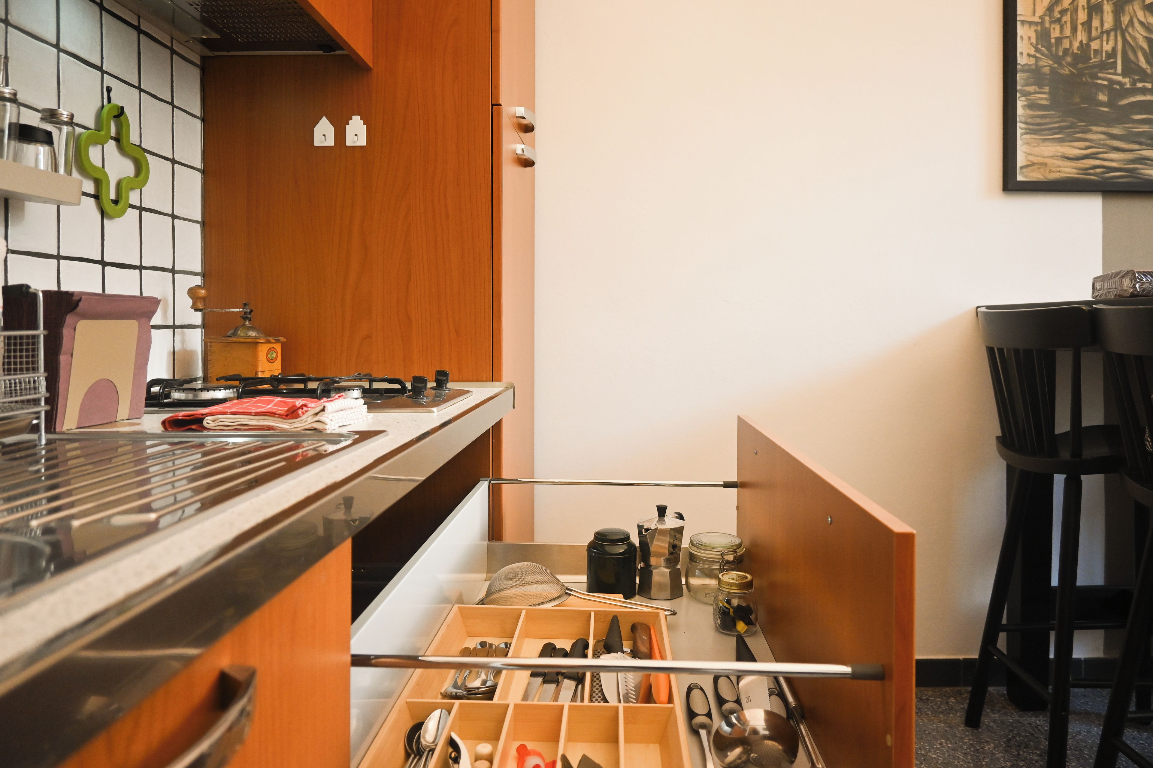 Een keuken met een houten kast, een fornuis en een lade-organizer met keukengerei.