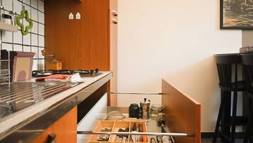 Een keuken met een houten kast, een fornuis en een lade-organizer met keukengerei.