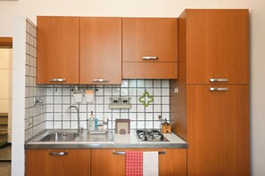 Una cucina con mobili in legno, un lavello in acciaio inossidabile e una stufa a gas.