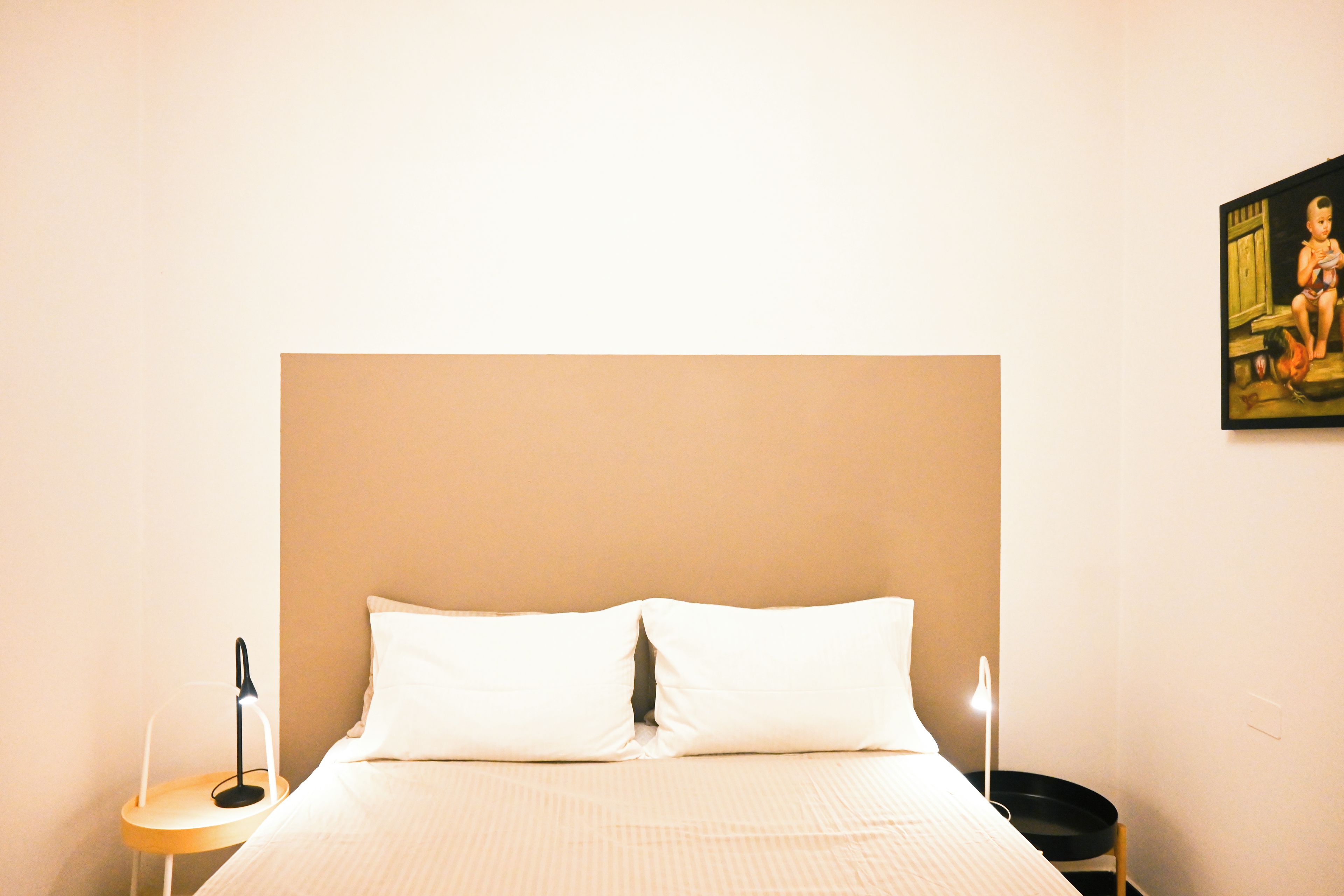 Una camera d'albergo con un letto grande, un comodino, una lampada e un quadro appeso al muro.