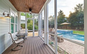 Un espacio al aire libre techado con piscina, terraza de madera y asientos.