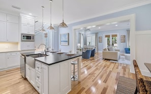 Una cocina moderna con una isla central, muebles blancos y electrodomésticos de acero inoxidable.