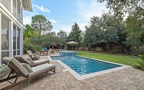 A backyard with a swimming pool, lounge chairs, and a patio area. - Chillville: Pool, Playground & Bikes (Santa Rosa Beach)