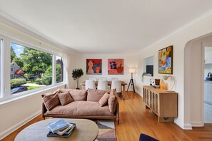 Ein modernes Wohnzimmer mit einer Couch, einem Esstisch und Kunstwerken an den Wänden.