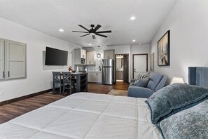 A modern bedroom with a large bed, a dining area, a kitchen, and a ceiling fan. - Sturgeon Bay Condo w Marina Slip and in law suite (Sturgeon Bay)