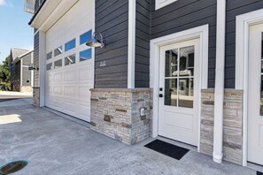 A residential garage with a stone accent wall, a white garage door, and a door with a glass panel. - Sturgeon Bay Condo w Marina Slip and in law suite (Sturgeon Bay)