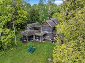 Een chalet met twee verdiepingen, een groot terras en een overdekt buitengebied, omringd door dicht bos.