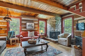 A cozy cabin interior with a stone fireplace, wooden walls, and a comfortable seating area. - Nostalgic rustic cabin on Kangaroo Lake-Dog Friendly w/ water access! (Baileys Harbor)