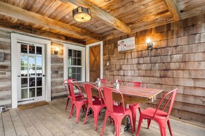 Het interieur van een houten chalet met een eettafel en rode stoelen, een houten plafond en een wandlamp.