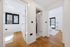 A modern interior with white walls, wooden flooring, and a view of a snowy landscape through a window. - Green Zone Apartment With Terrace And Parking (Zagreb)