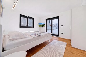 Une chambre moderne équipée d’un lit, d’un téléviseur à écran plat et offrant une vue sur un paysage enneigé grâce à une porte-fenêtre coulissante.