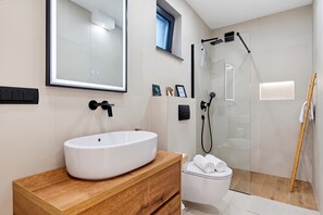 A modern bathroom with a large mirror, a white sink, a shower, and a wooden vanity. - Green Zone Apartment With Terrace And Parking (Zagreb)