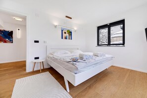 A modern bedroom with a white bed, a small white table, and a painting on the wall. - Green Zone Apartment With Terrace And Parking (Zagreb)