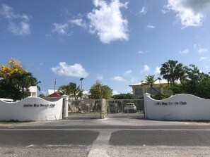 A gated entrance to a beach club with a clear sky and palm trees. - TI PARADISE Studio SXM Baie Nettlé on the Beach (Marigot)