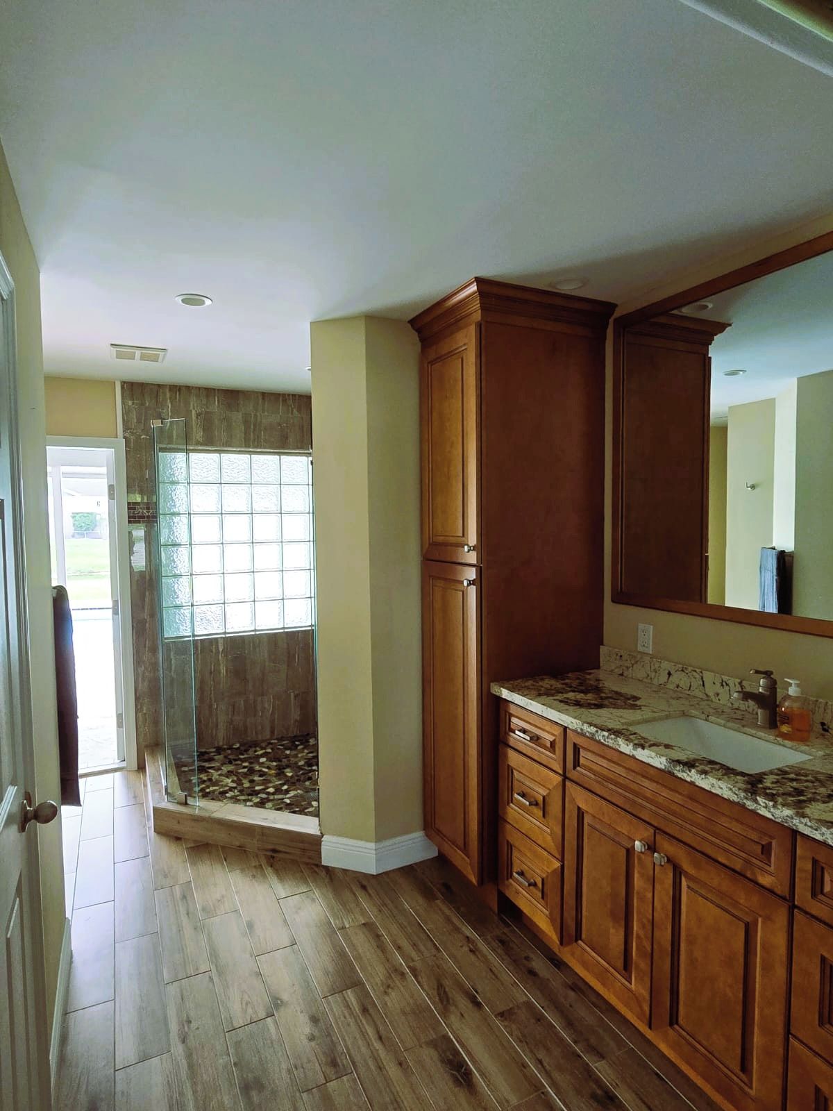 A kitchen with wooden cabinets, a marble countertop, and a large window.