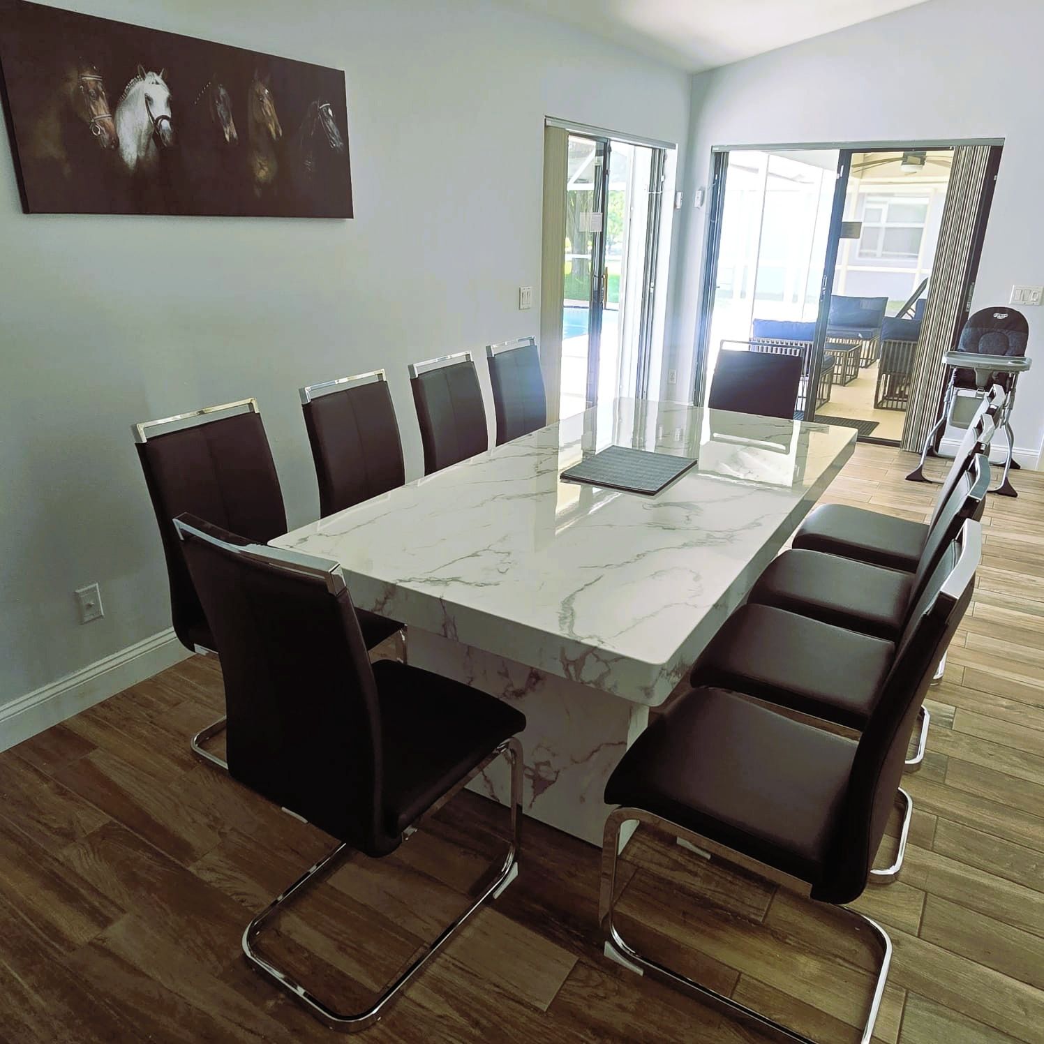 A conference room with a marble table and black chairs, large windows, and a view of the outdoors.