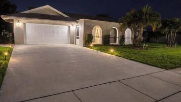 A residential house with a garage, a driveway, and a well-lit front yard.