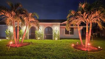 A building with a symmetrical facade, arched windows, and a well-maintained lawn with palm trees.