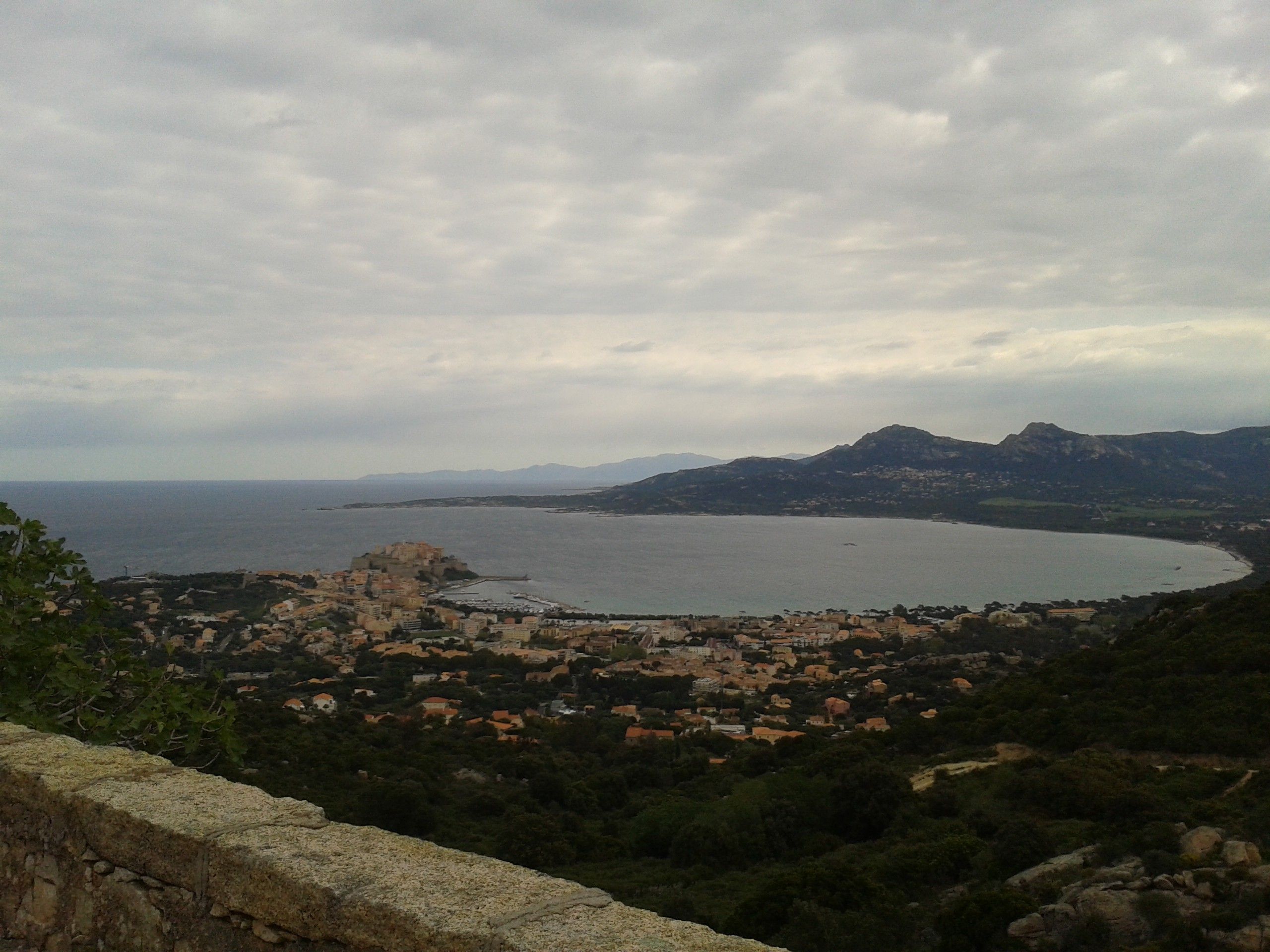 Une ville côtière offrant une vue sur la mer et les montagnes au loin.