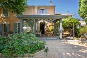Une maison dotée d’un patio couvert, d’un jardin et de mobilier d’extérieur.