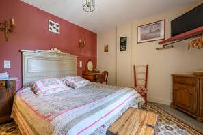 Ein Schlafzimmer mit Bett, Kommode, Stuhl und Bildern an den Wänden.