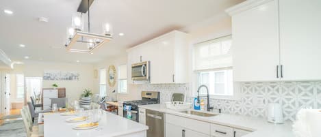 Una cocina moderna con armarios blancos, una isla central y un comedor con mesa para cuatro.