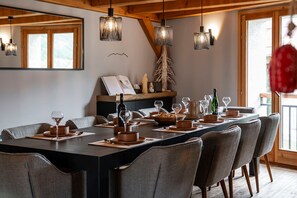 A dining area with a long table set for six, wooden chairs, and hanging pendant lights. - Le Refuge du Bez - Pistes de ski à 100m (La Salle-les-Alpes)