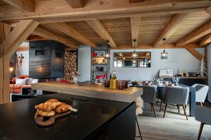 Cozinha moderna com ilha central, vigas de madeira e área de jantar com cadeiras e mesa.