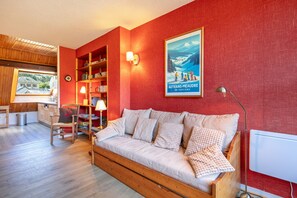 Ein gemütliches Wohnzimmer mit einer Holzsofa, einem Bücherregal und einem Poster an der Wand.