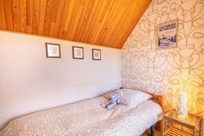 A bedroom with a single bed, a wooden ceiling, and a wall with framed pictures. - La Moucherolle - Station de ski accessible à pied (Méaudre)