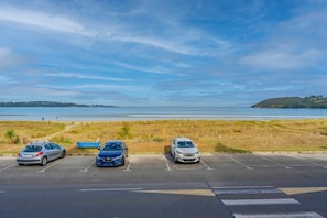 Een parkeerplaats met drie auto's, een gazon en uitzicht op het strand en de zee.