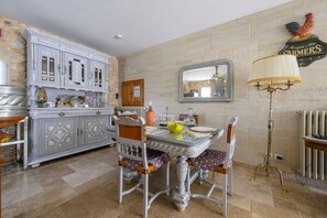 A dining area with a white table, chairs, and a decorative lamp. - Le Coin Rétro - Proche d'Avignon (Le Thor)