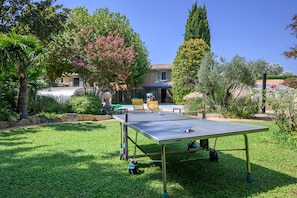 A ping pong table in a grassy yard with a house in the background. - Le Coin Rétro - Proche d'Avignon (Le Thor)