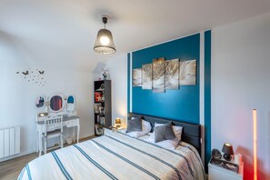A bedroom with a bed, bedside tables, a desk, a bookshelf, and a wall art piece. - La Parenthèse Morbihannaise (Saint-Marcel)
