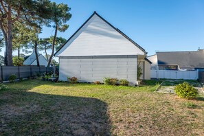 Ein eingeschossiges Haus mit Satteldach, umzäuntem Garten und kleinen Gartenflächen.