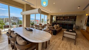 A modern hotel interior with a dining area, seating, and a bar. - Jacana Serenity 206 | Bucerias Beach & Rooftop Infinity Pool (Nuevo Vallarta)