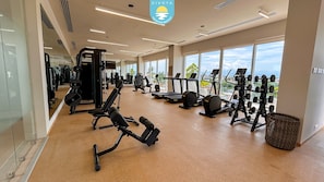 A gym with various exercise equipment, large windows, and a view of the outdoors. - Jacana Serenity 206 | Bucerias Beach & Rooftop Infinity Pool (Nuevo Vallarta)