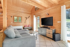 A wooden cabin interior with a sofa, a television, and a cabinet. - Chalet Caribou - Pour 6 avec terrasse (Ventron)