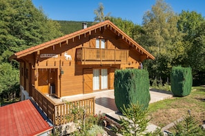 A wooden chalet with a balcony, a sign reading 'LI CARIBOU', and a red-roofed structure to the left. - Chalet Caribou - Pour 6 avec terrasse (Ventron)