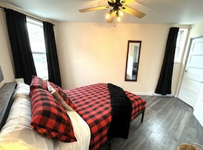A bedroom with a bed, a ceiling fan, a window with curtains, and a door. - The hideaway of Limoilou, a cozy little urban nest (Québec)
