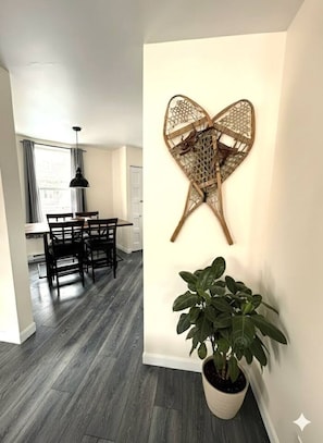 A modern interior with a dining area featuring a dark wood table and chairs, a large potted plant, and a wall-mounted decorative piece. - The hideaway of Limoilou, a cozy little urban nest (Québec)