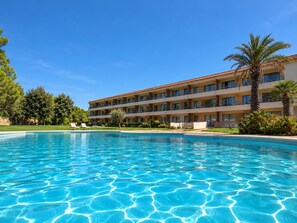 Ein Hotel mit Pool, mehreren Balkonen und Palmen.