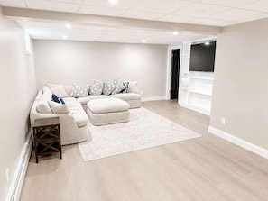 Una sala moderna con un sofá modular, un reposapiés y almohadones estampados.