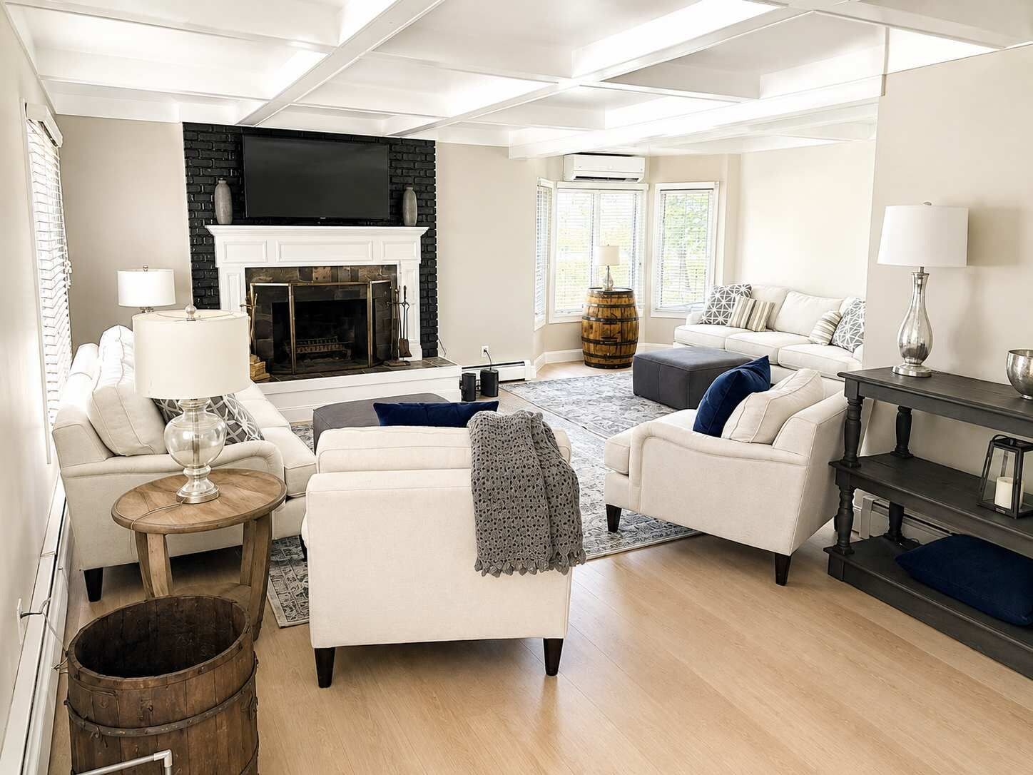 A modern living room with a fireplace, white sofas, a coffee table, and a TV.