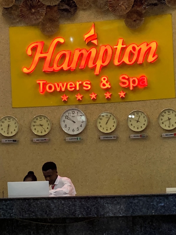 A hotel sign with 'Hampton Towers & Spa' and clocks indicating different time zones.