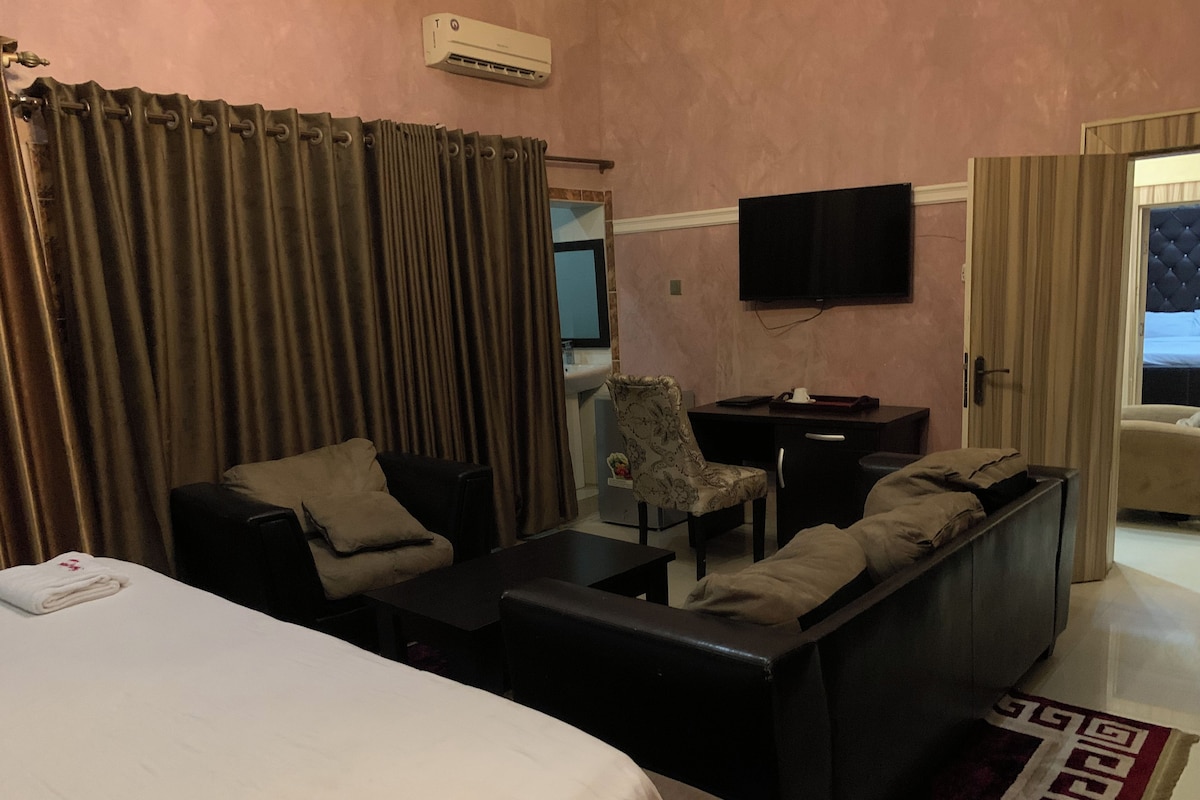 A hotel room with a bed, a sofa, a desk, and a chair.