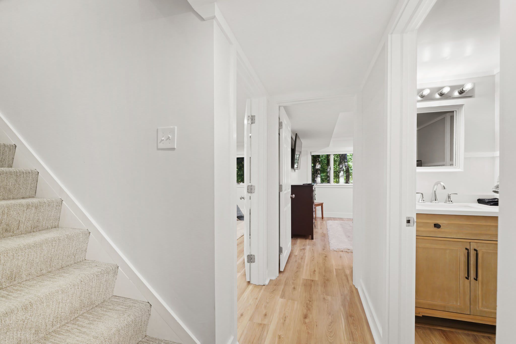 Un intérieur moderne comprenant un escalier, un coin cuisine et un couloir menant à une chambre.